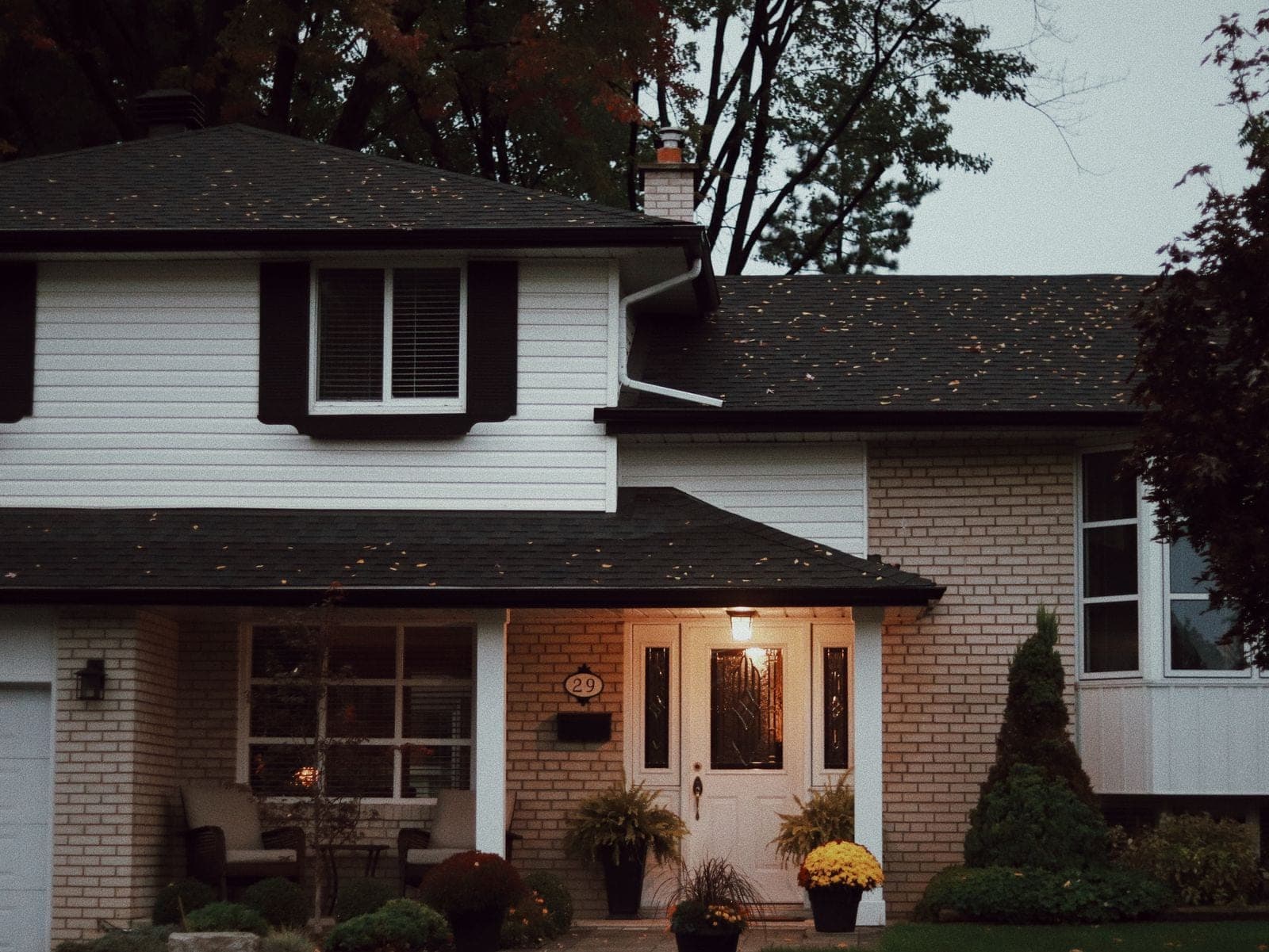 Two-story home with a dark asphalt shingle roof at dusk