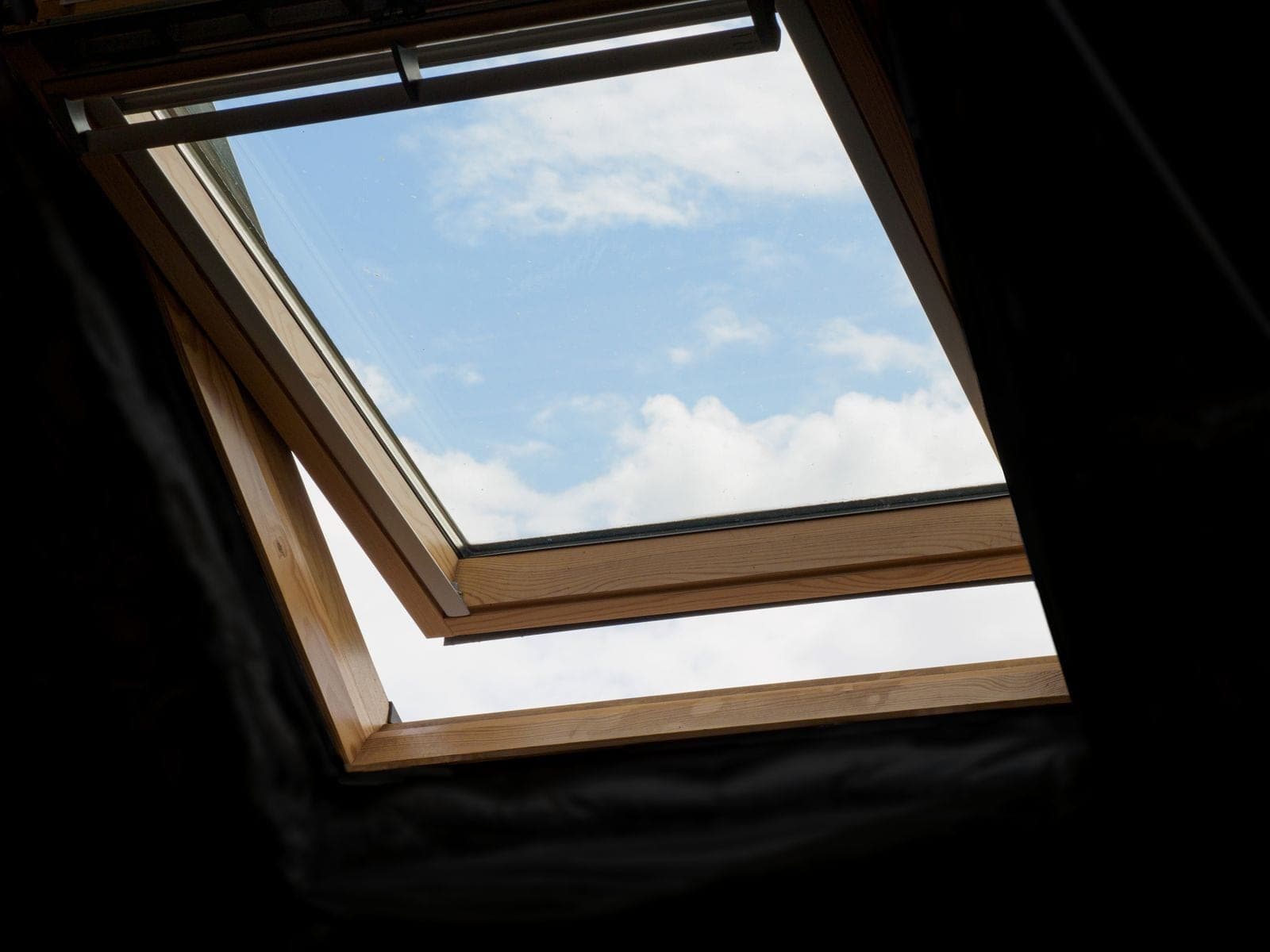 Open skylight window seen from inside with blue sky above