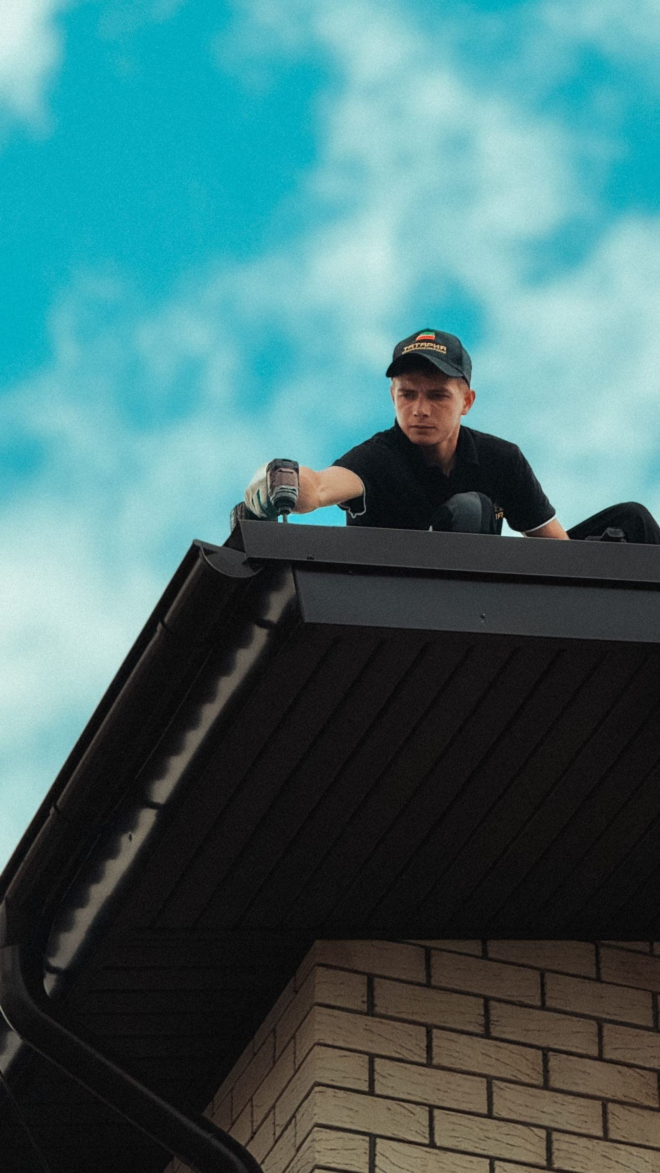 Roofer working at the edge of a dark roof