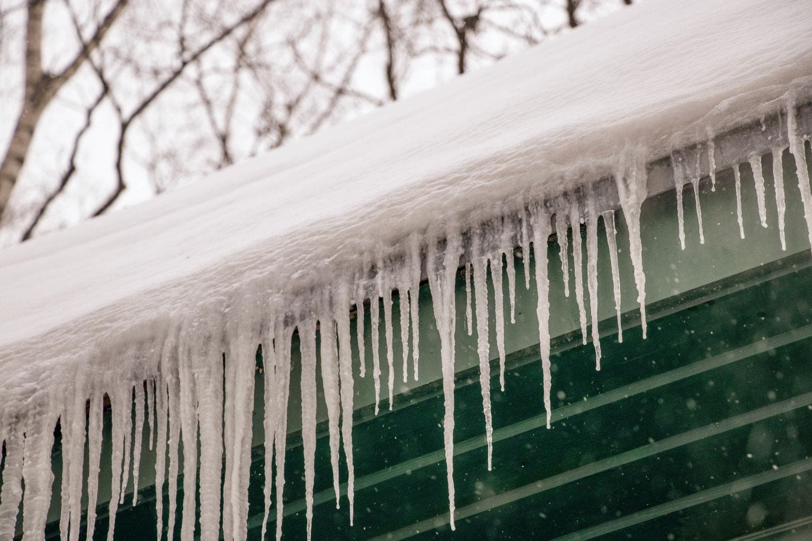 Long icicles hanging from a snow-covered roof edge