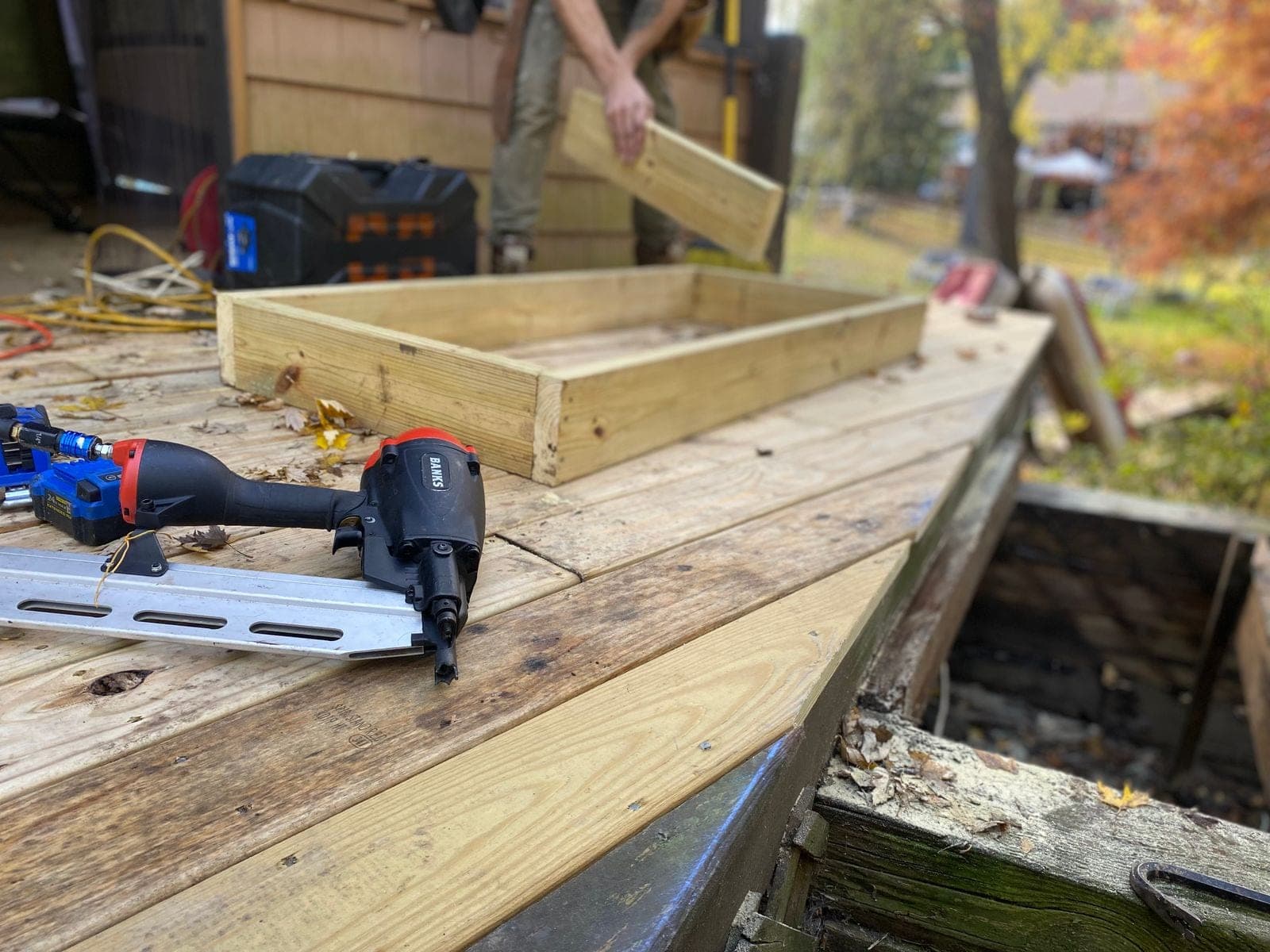 Nail gun and battery tools on a wood deck work site